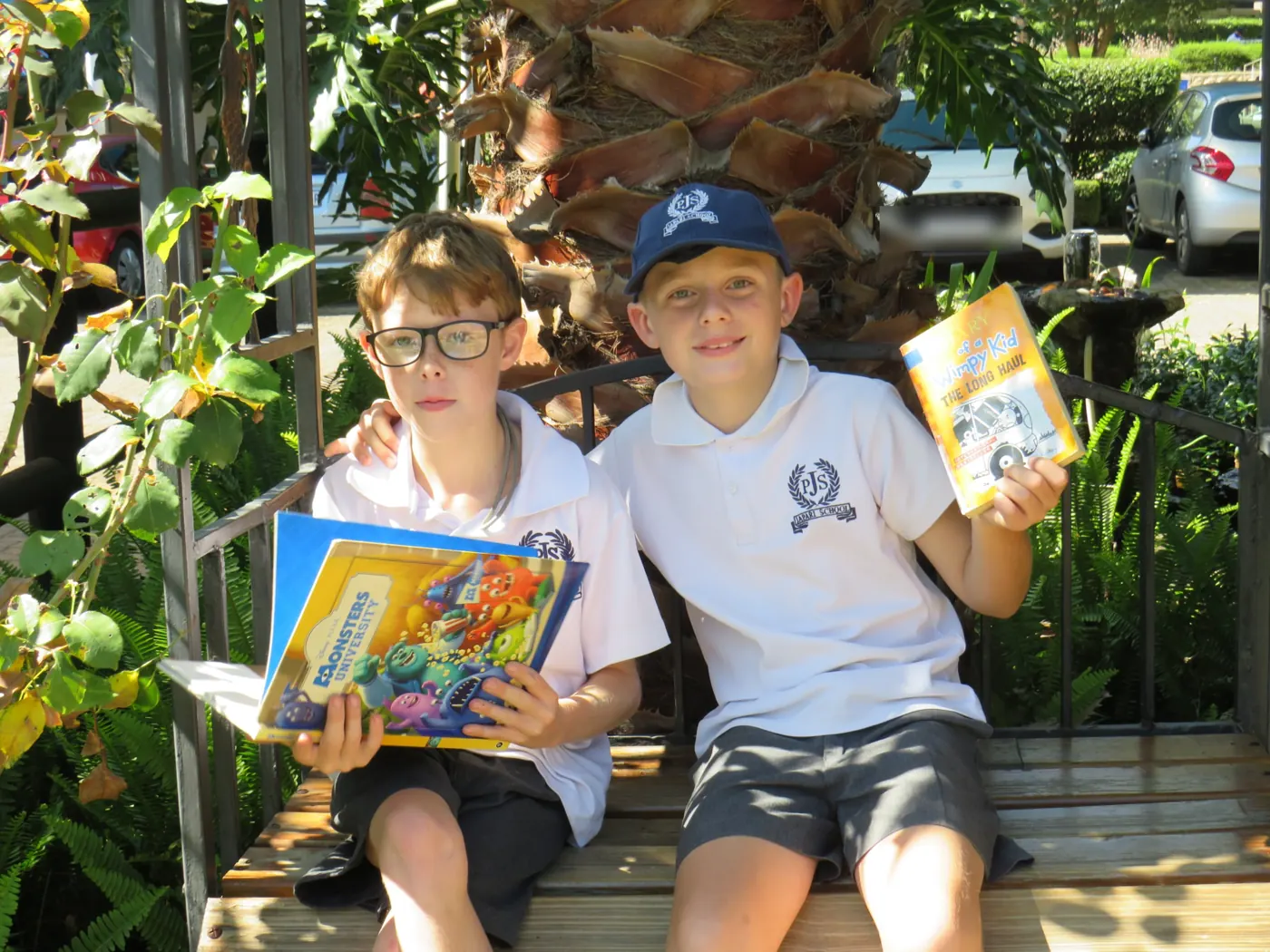Two pupils sitting on a garden bench with their books