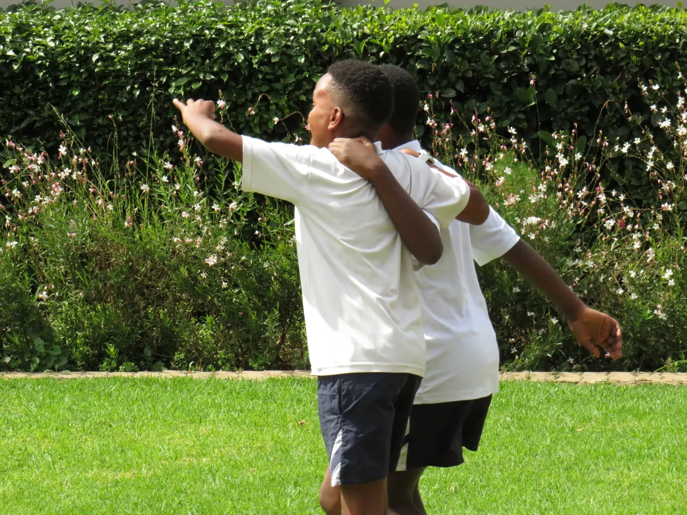 Two friends with their arms around each other on the school field