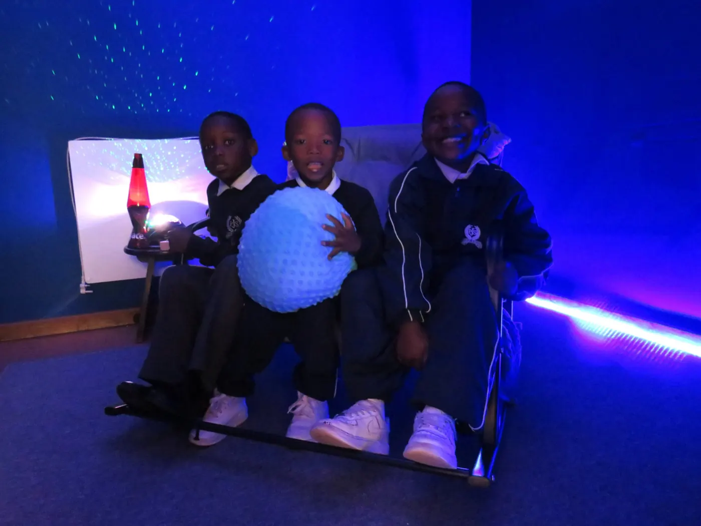 Three Japari pupils working with a textured therapy ball in the sensory room